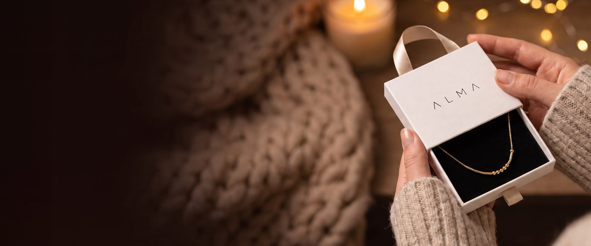 Mani che porgono la scatola regalo ALMA con la collana codice Morse